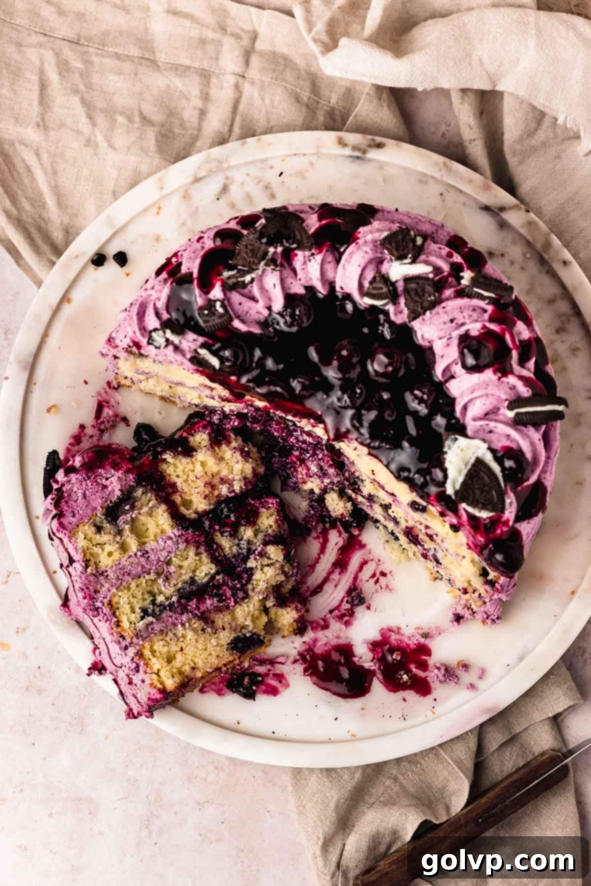 Cut blueberry cake with slice on marble cake plate