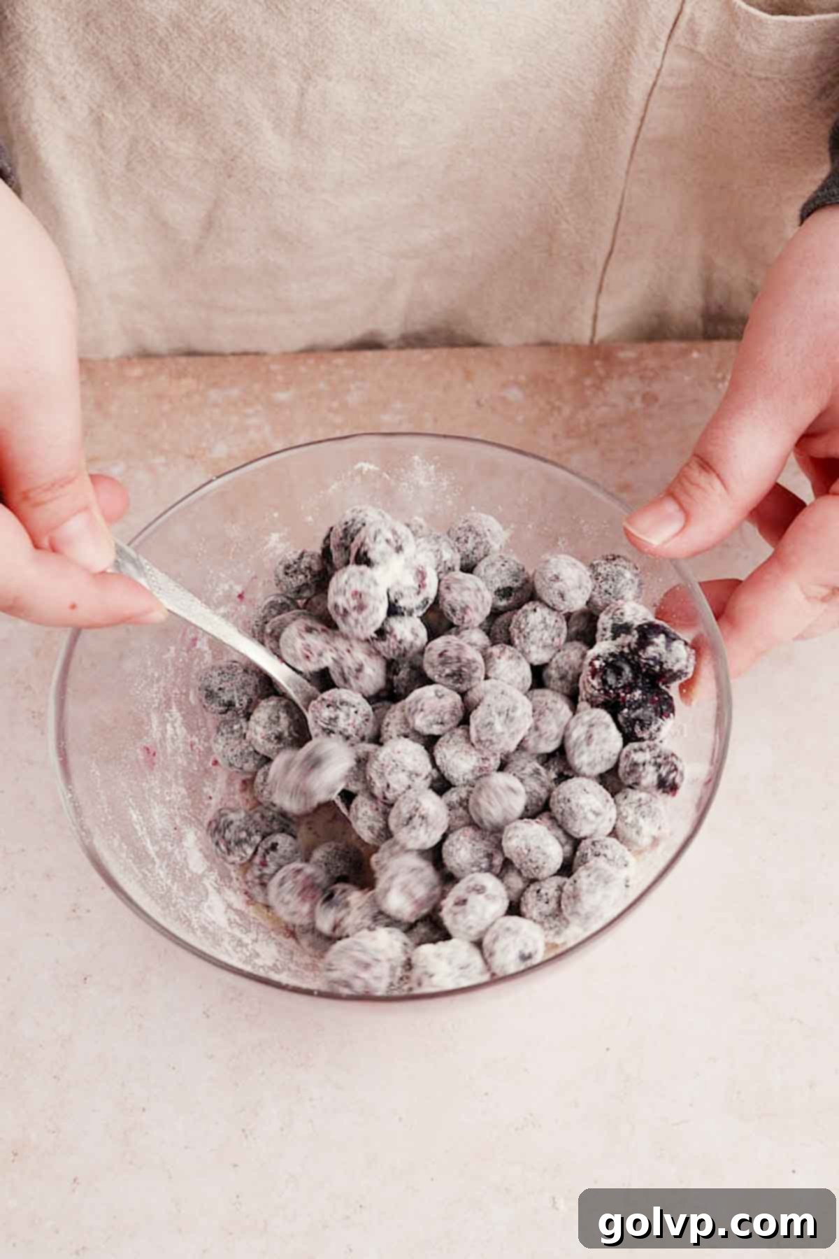 coating blueberries in flour in a small bowl