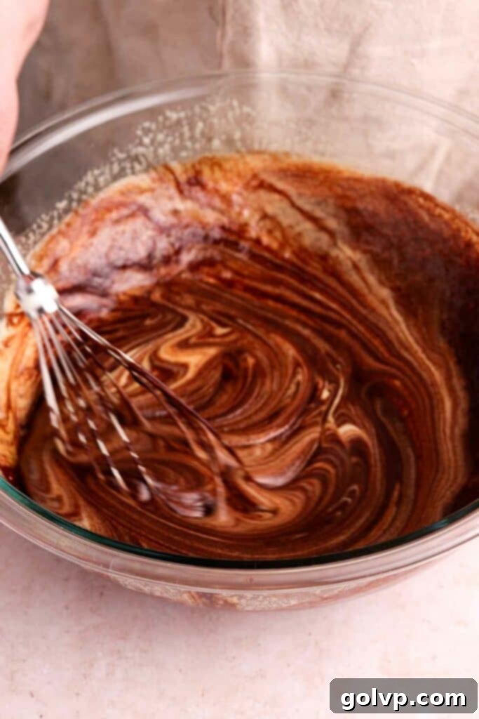 Gently folding melted chocolate into the whisked egg and sugar mixture for brownies