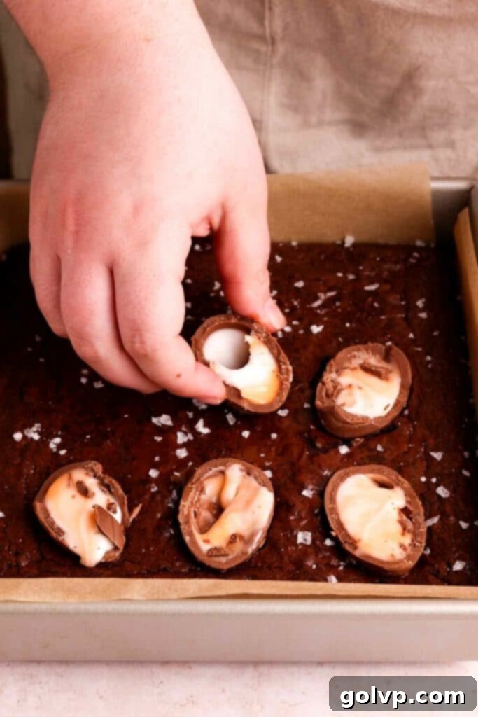 Placing halved Cadbury Creme Eggs on top of warm, freshly baked brownies