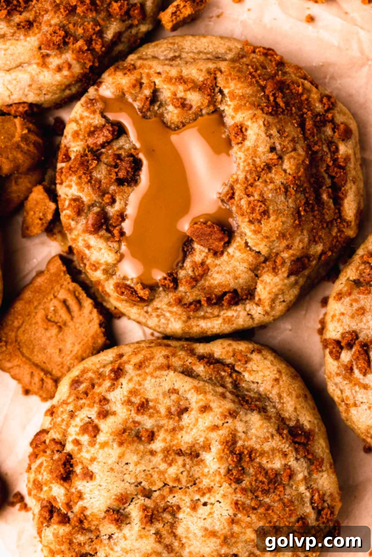 A baked Biscoff stuffed cookie showing its golden exterior and a glimpse of the melted Biscoff cookie butter filling, sitting on a wire cooling rack after being removed from the oven.