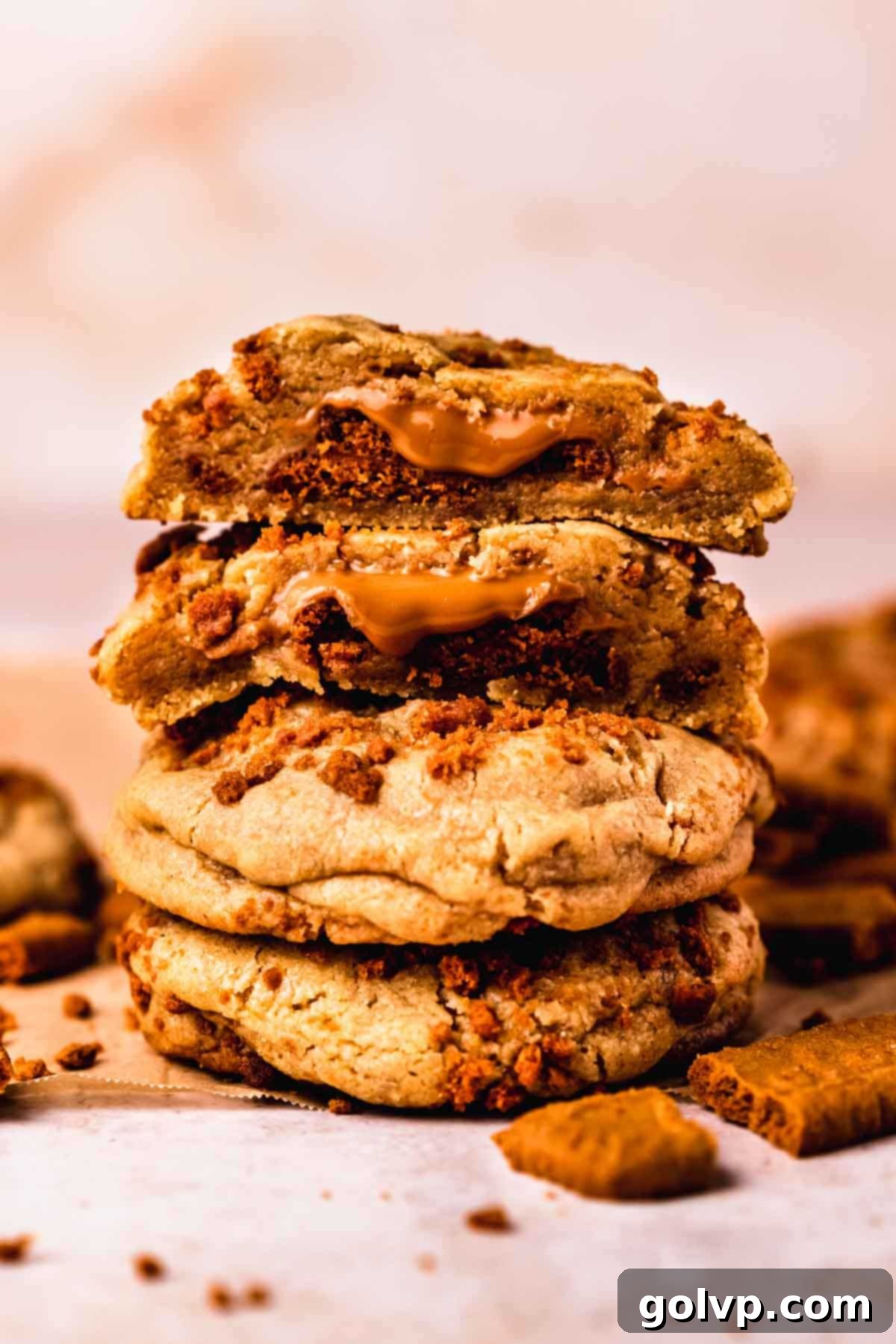 A delectable stack of three golden-brown Biscoff stuffed cookies, showcasing their thick, soft texture and a hint of the irresistible cookie butter filling, inviting a bite.