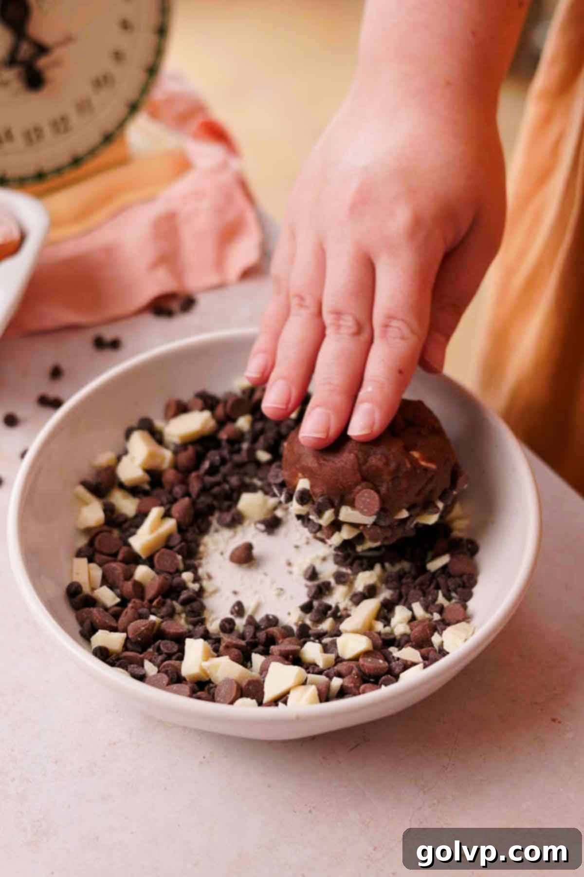 Rolling the top of cookie dough balls into chocolate chips for coating