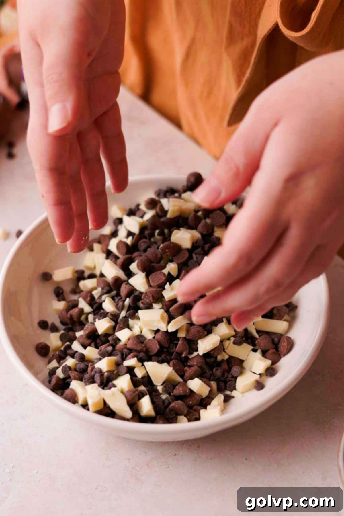 Mixing various chocolate chips and chopped chocolate in a bowl