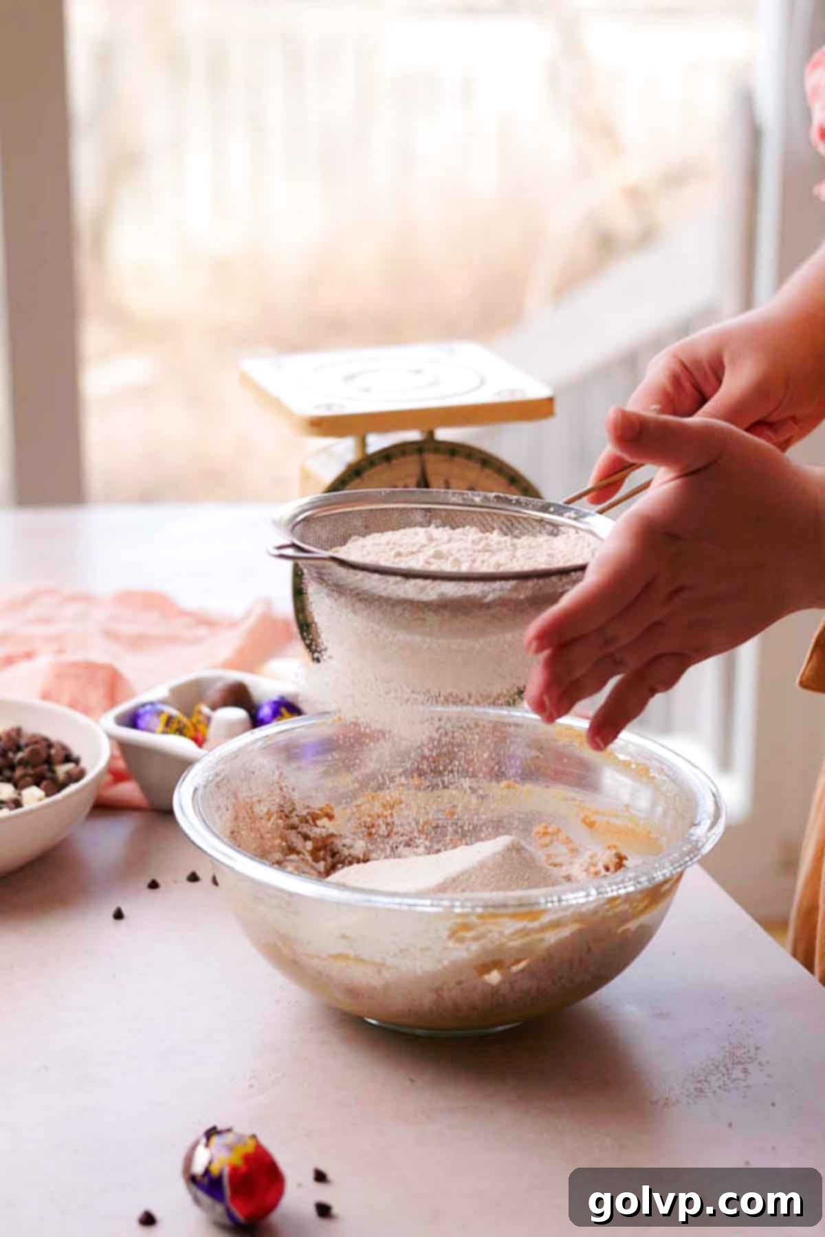 Sifting dry ingredients like flour into creme egg cookie dough