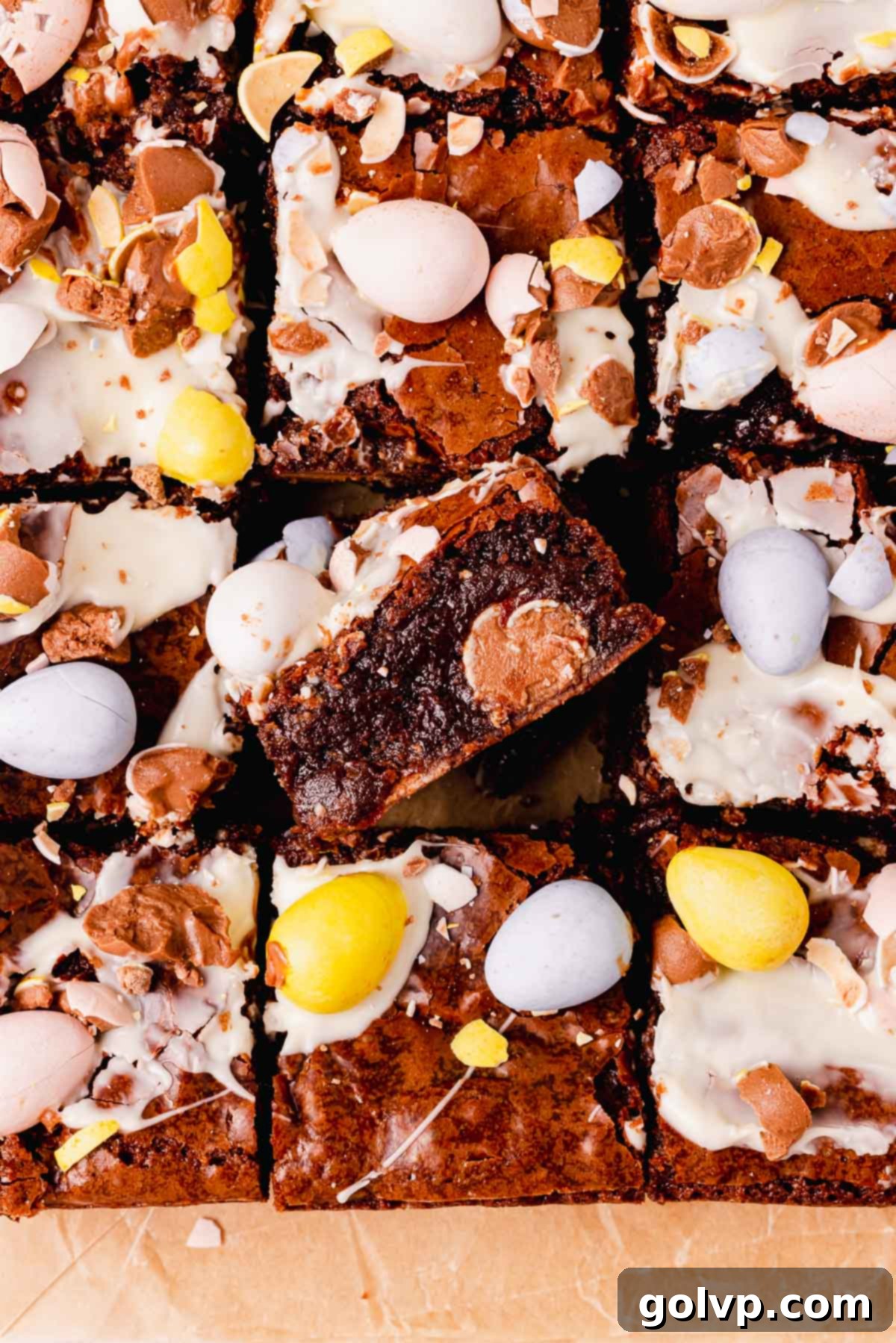 brownies topped and filled with mini eggs on parchment paper, showcasing their fudgy texture and crackly tops