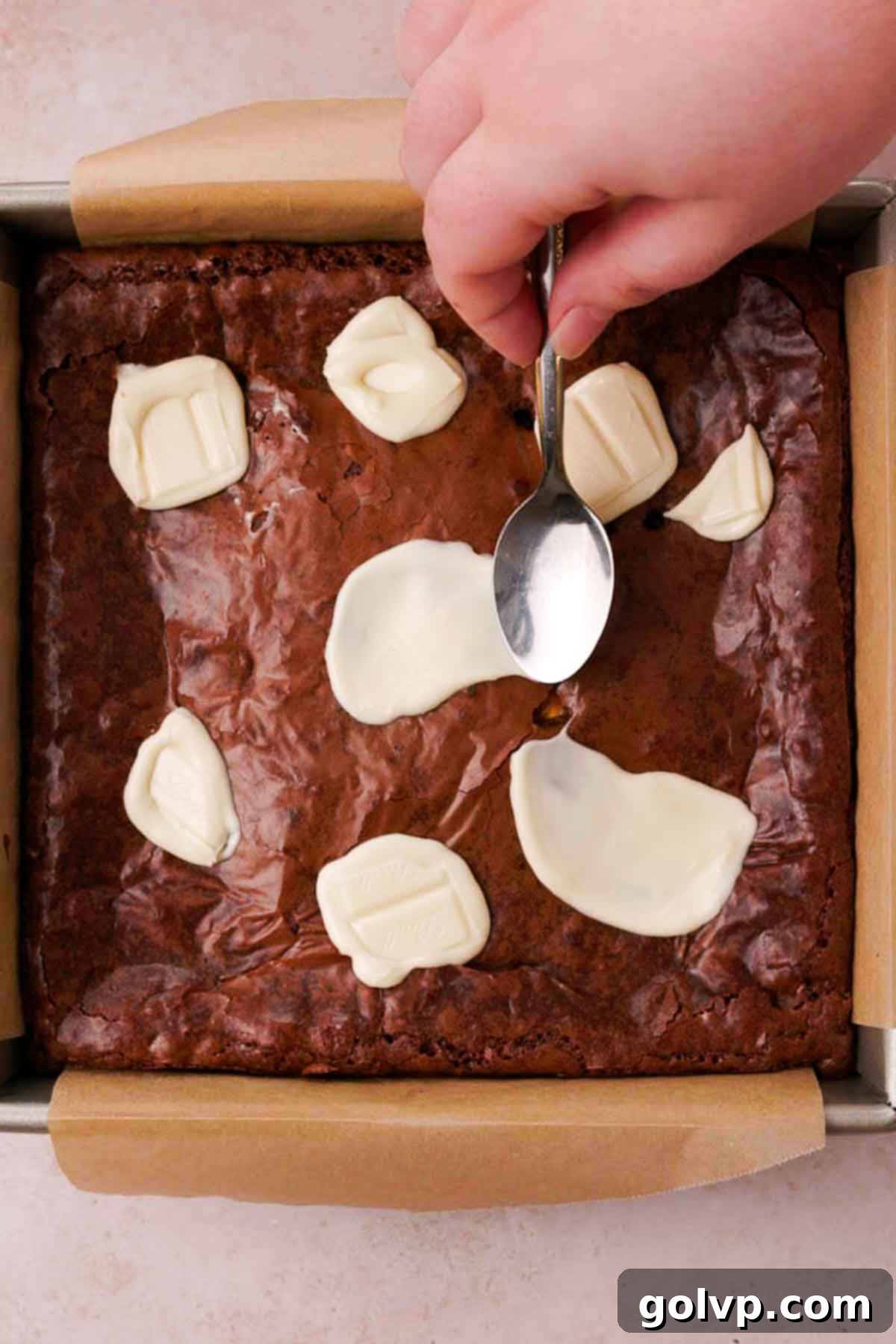 smearing melted white chocolate with the back of a spoon onto baked brownie top for splatter effect