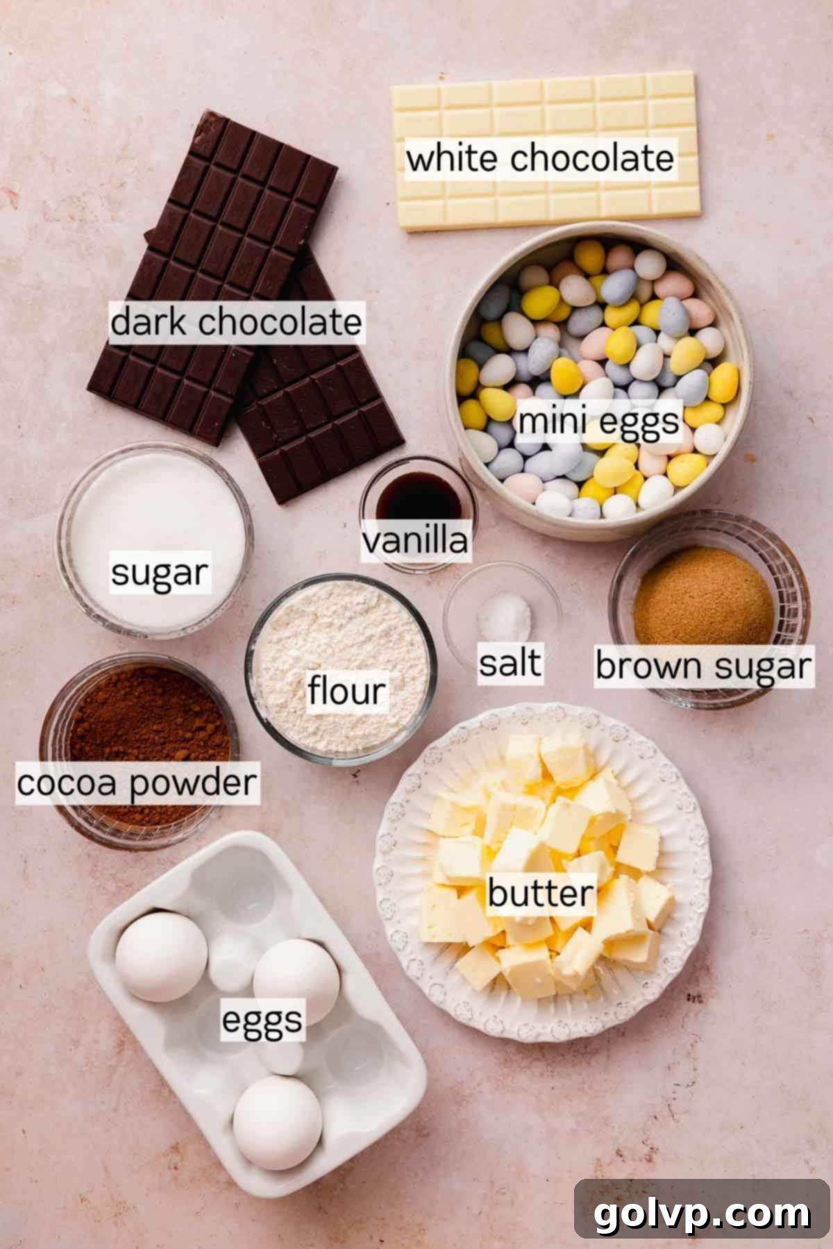 bowls filled with ingredients for mini egg brownies, including chocolate, butter, eggs, and mini eggs