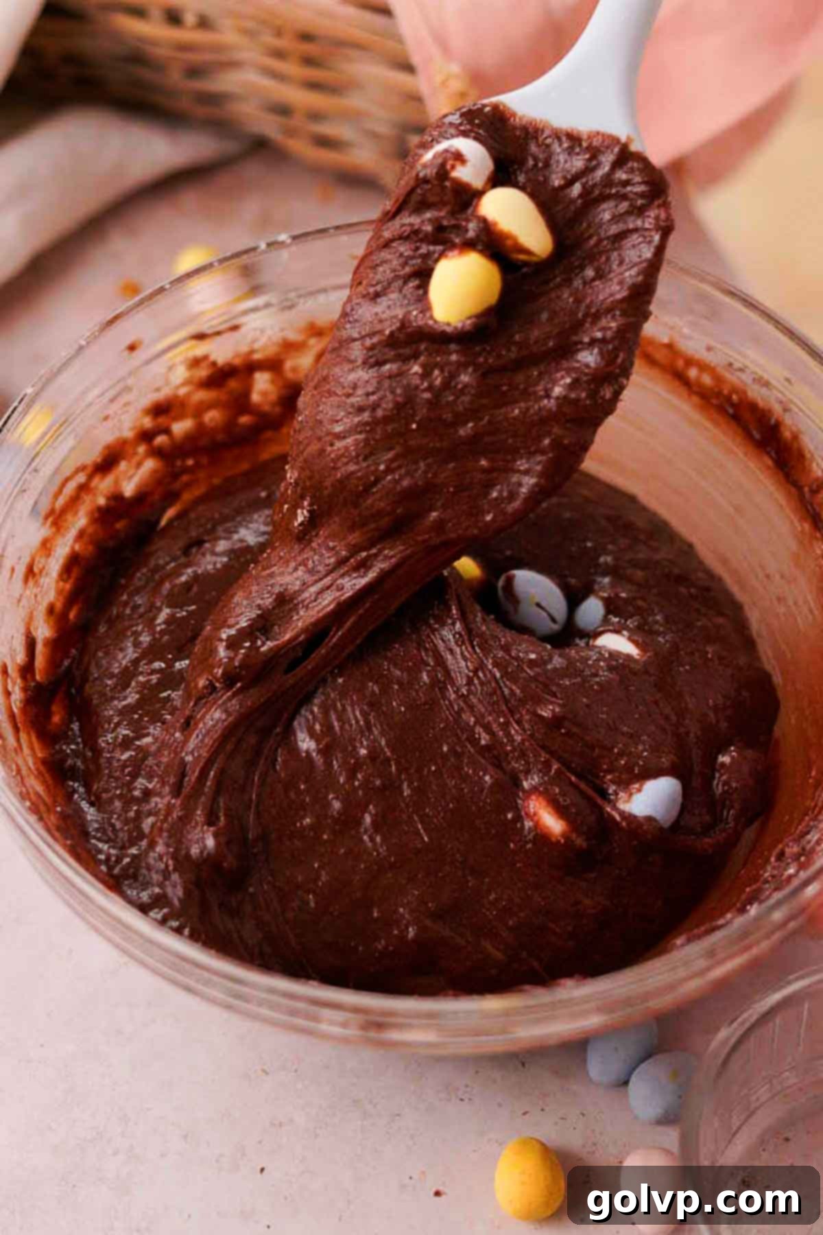 folding chocolate mini eggs into brownie batter with a silicone spatula