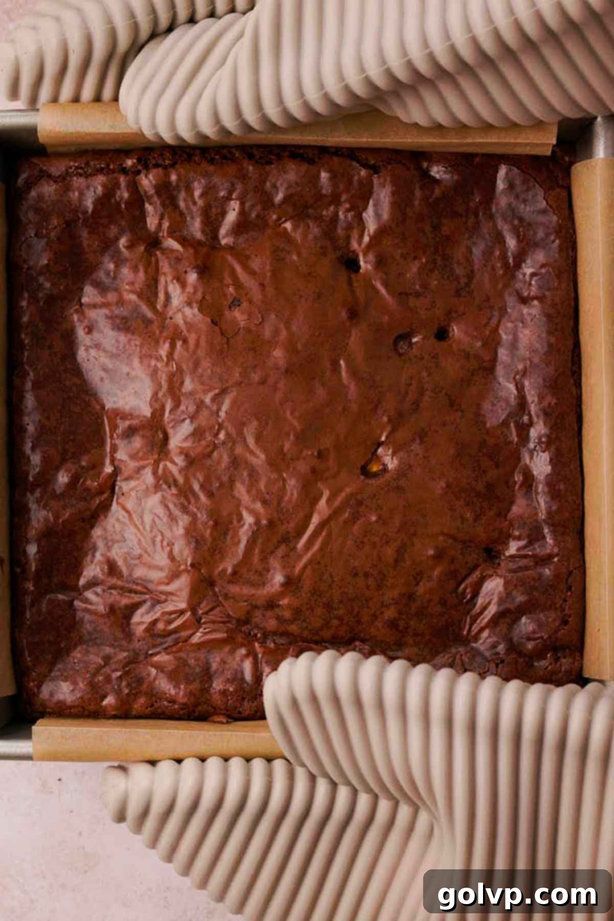 holding baking pan with hot mini egg brownies using oven mitts, freshly baked