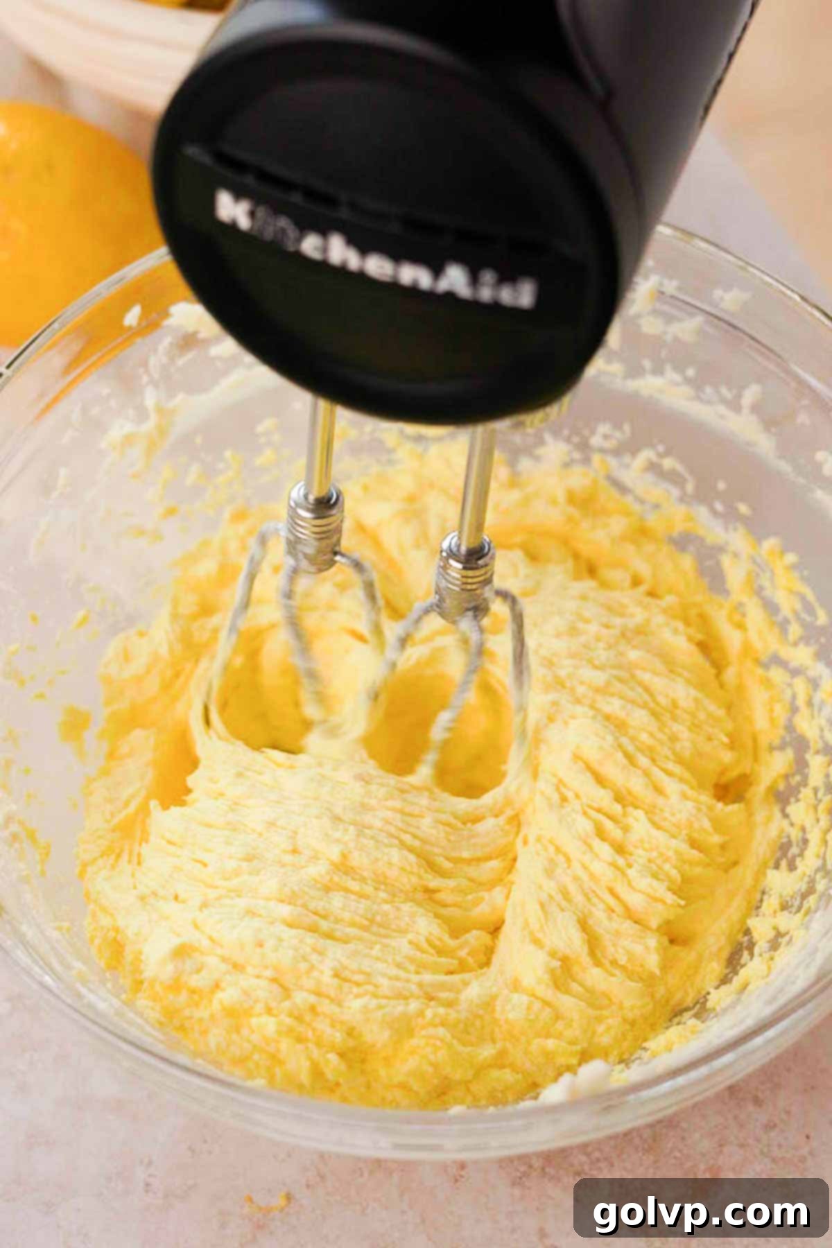 Mixing the wet ingredients for lemon curd cookies, including eggs and lemon juice, with an electric mixer