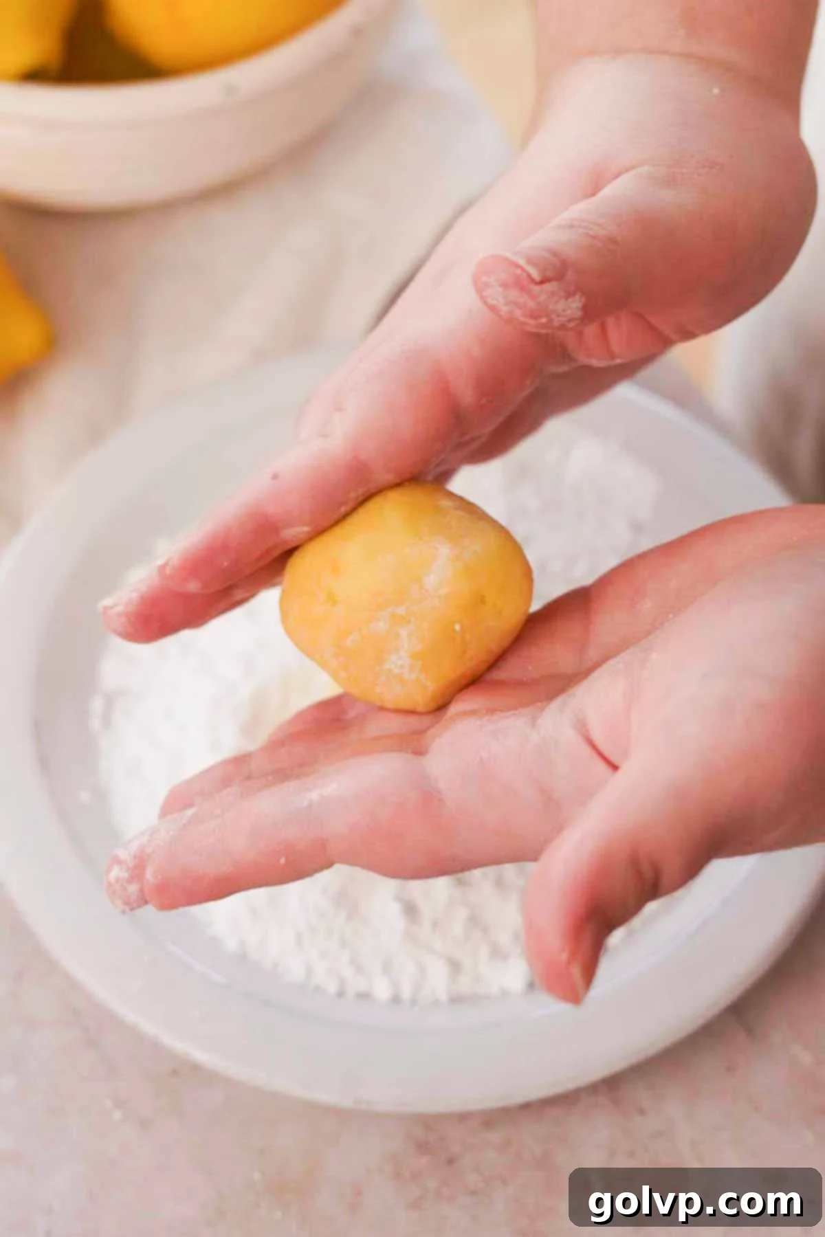 Rolling portions of cookie dough between hands to form perfectly round, smooth balls