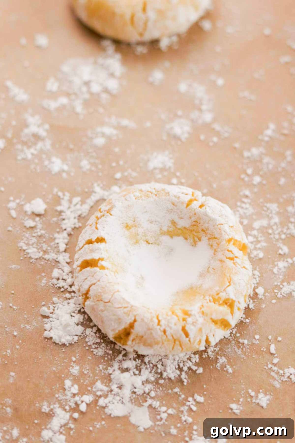 Cookie dough balls rolled in powdered sugar with visible indents in their centers, ready for chilling