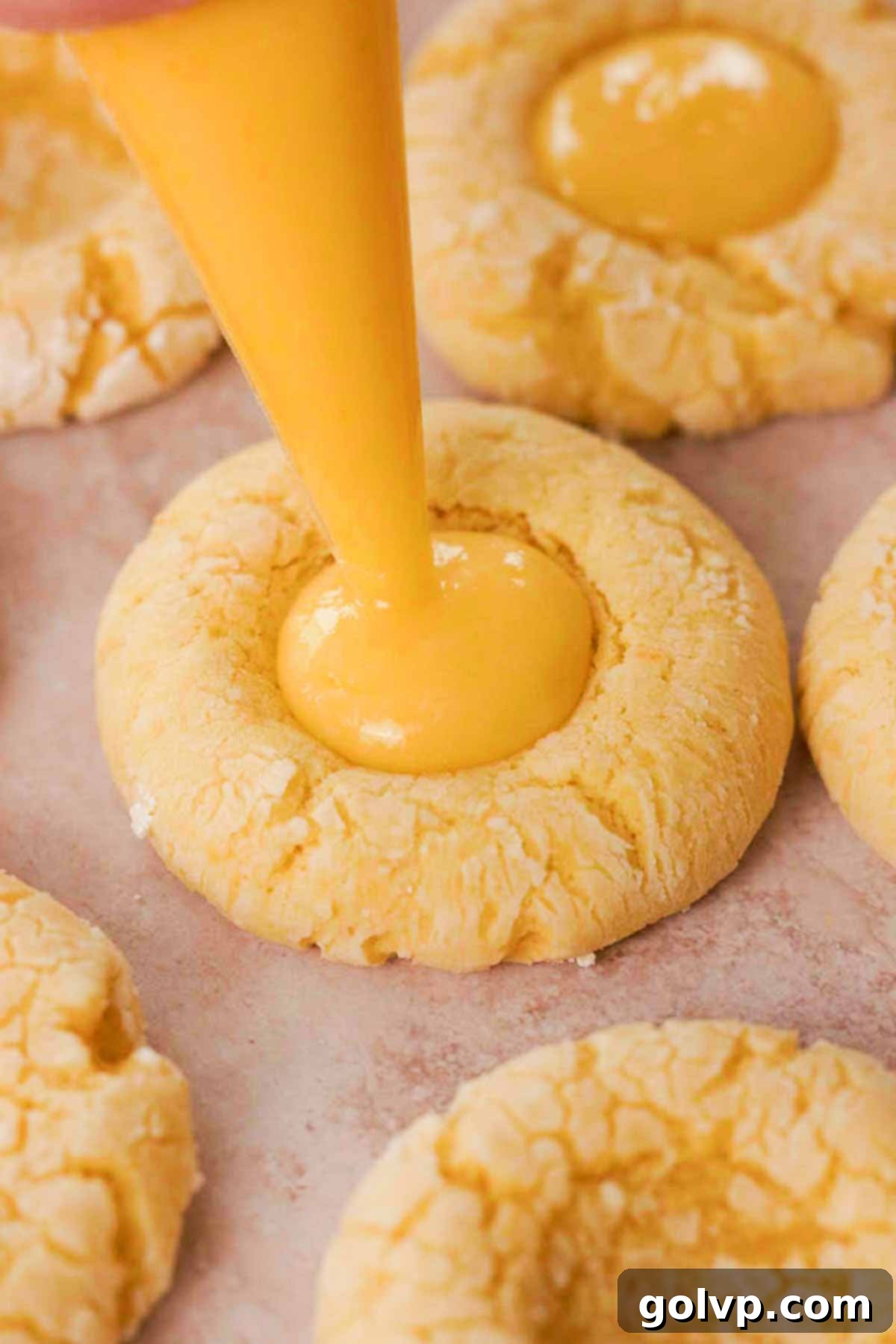 Filling the centers of cooled lemon cookies with bright yellow lemon curd using a piping bag
