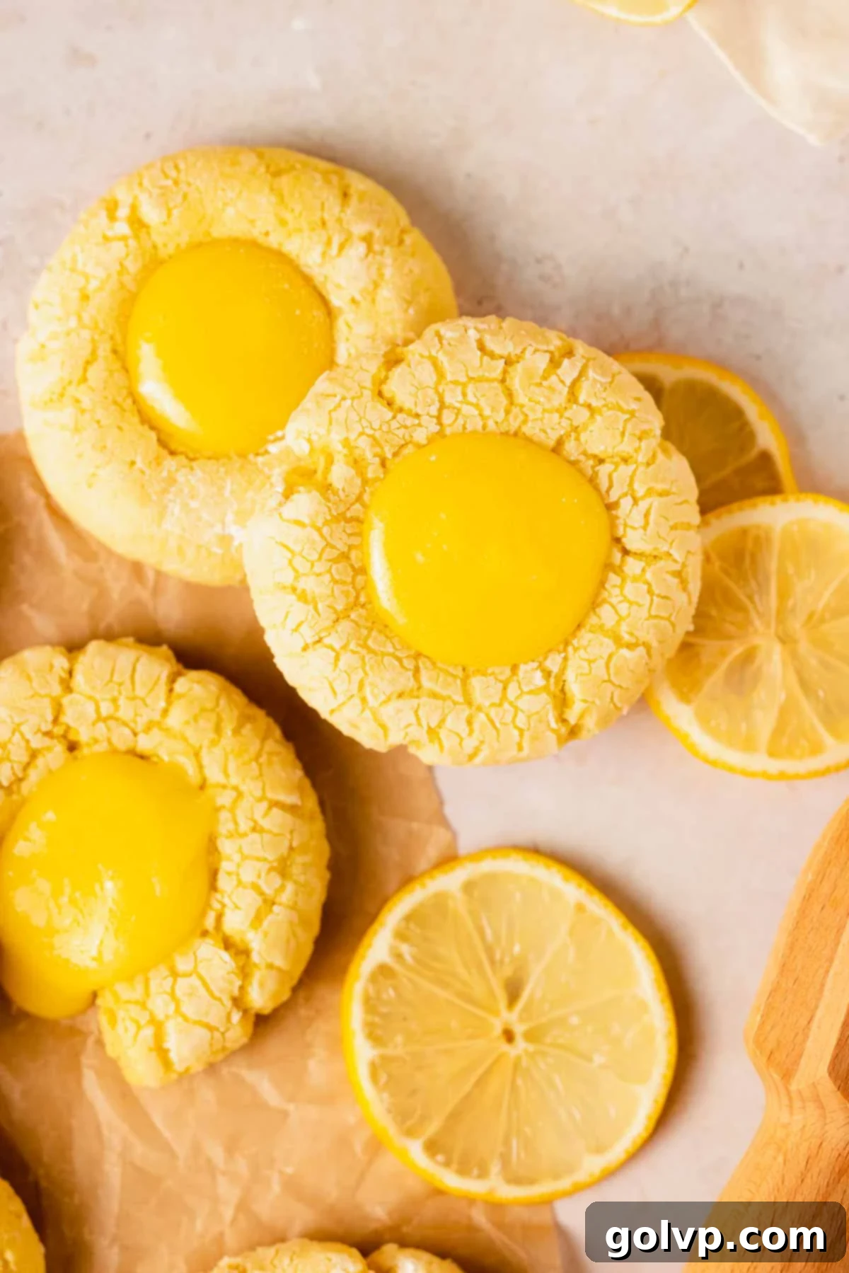 Delicious crinkle cookies filled with vibrant lemon curd, arranged neatly on parchment paper after baking