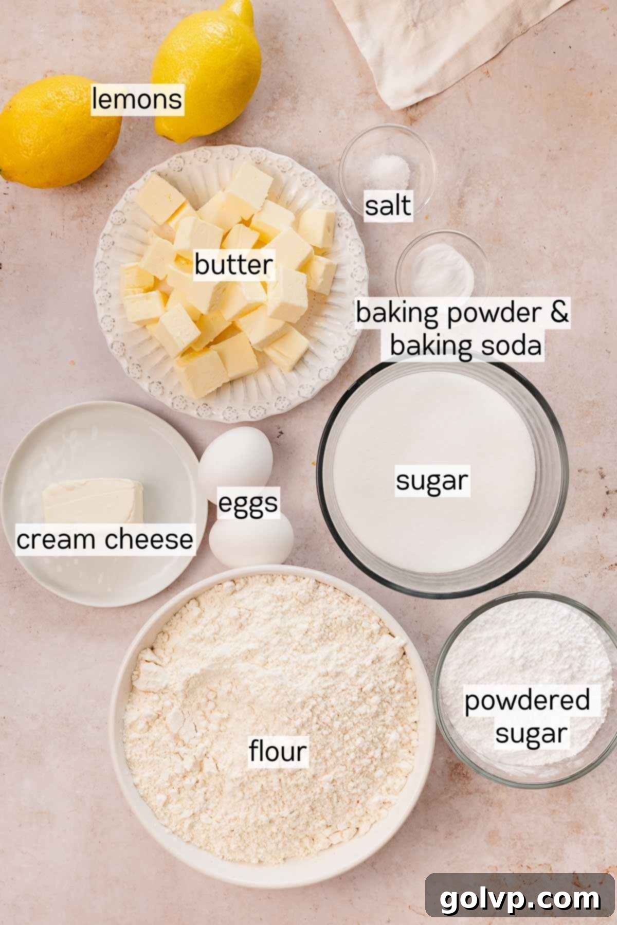 A selection of fresh ingredients for lemon curd cookies, including lemons, butter, eggs, sugar, and flour in various bowls