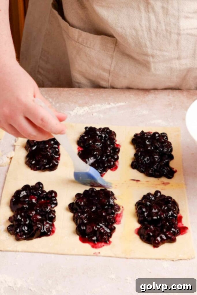 Filling pastry with blueberry filling and brushing with egg wash for sealing
