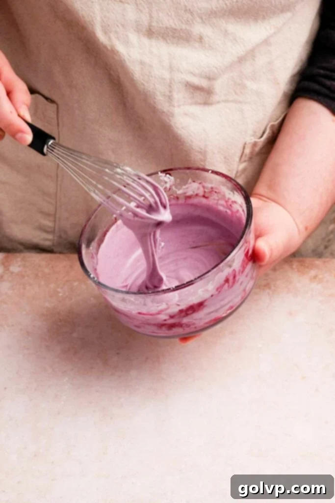 Whisking blueberry glaze in a bowl until smooth and creamy