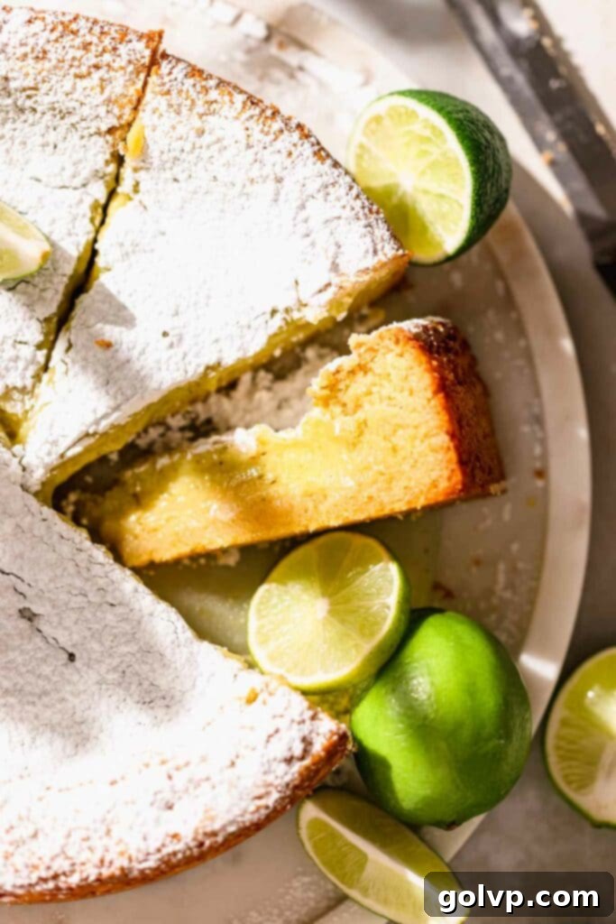 Sliced gooey lime butter cake revealing soft base and tangy filling, garnished with powdered sugar.