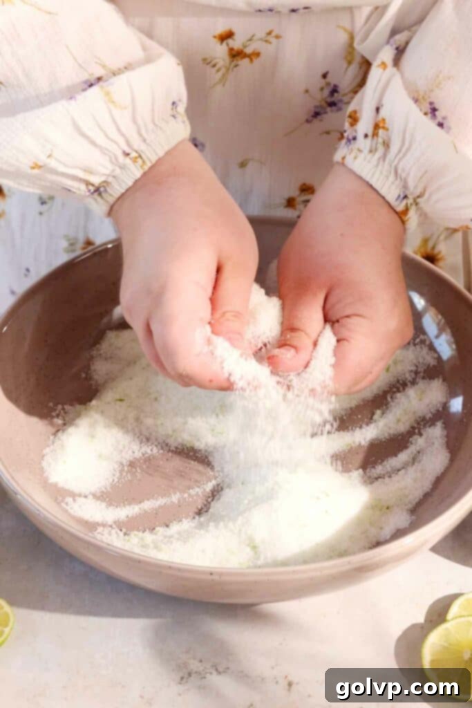 Hands rubbing lime zest and sugar together in a bowl, showing the fragrant mixture.