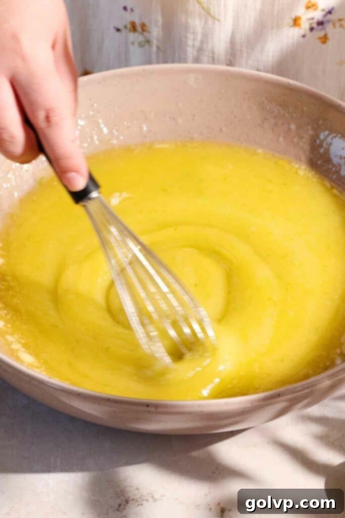 Whisking wet ingredients for the lime cake batter in a bowl.