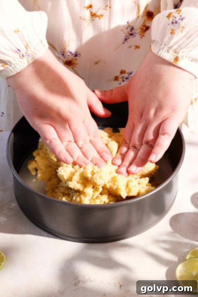 Pressing lime cake batter evenly into the bottom of a baking pan.