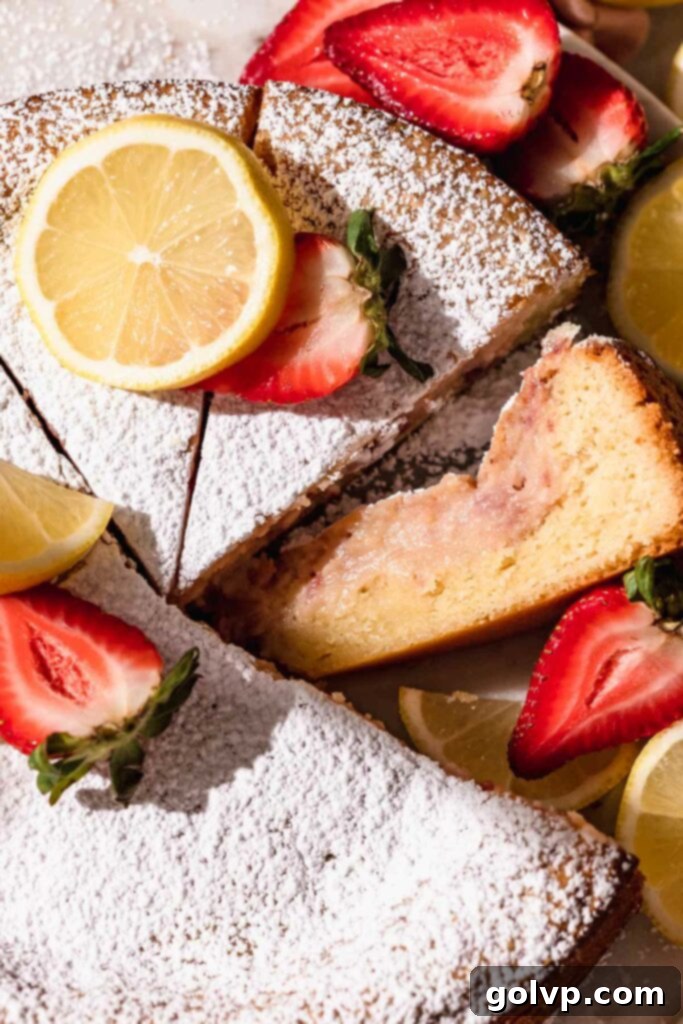 Closeup of a freshly baked strawberry lemon butter cake slice, showcasing its gooey strawberry center and golden-brown crust.