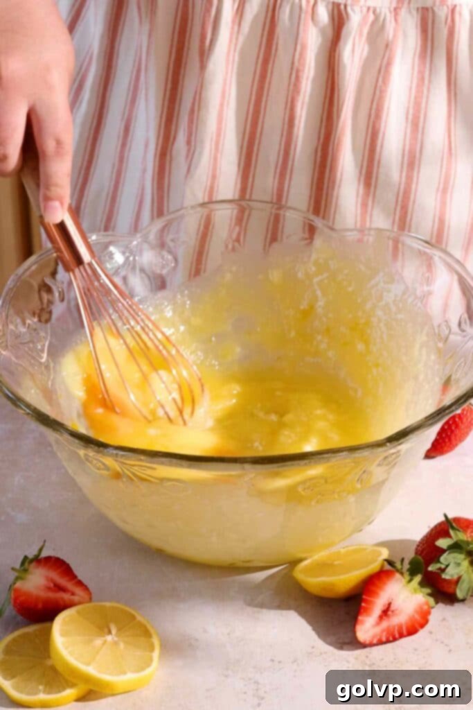 Whisking wet ingredients (melted butter, egg, lemon juice) into the lemon-infused sugar.