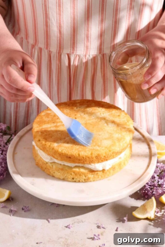 Brushing a baked cake layer with fragrant lilac syrup before frosting