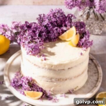 Semi naked layer cake topped with fresh lilacs and lemon wedges