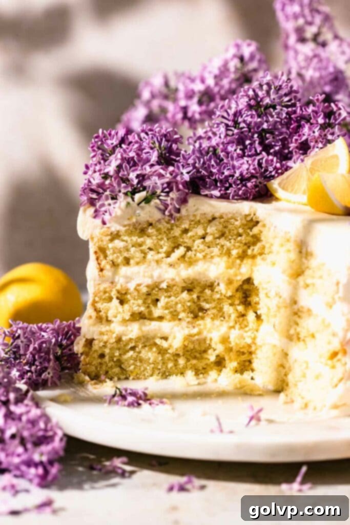 Sliced lilac lemon cake on a marble cake stand, showing moist layers and creamy frosting