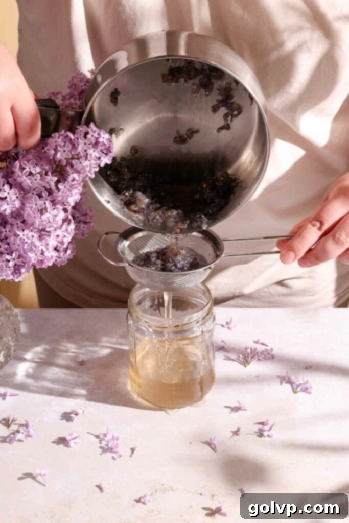 Straining homemade lilac syrup through a sieve to remove petals