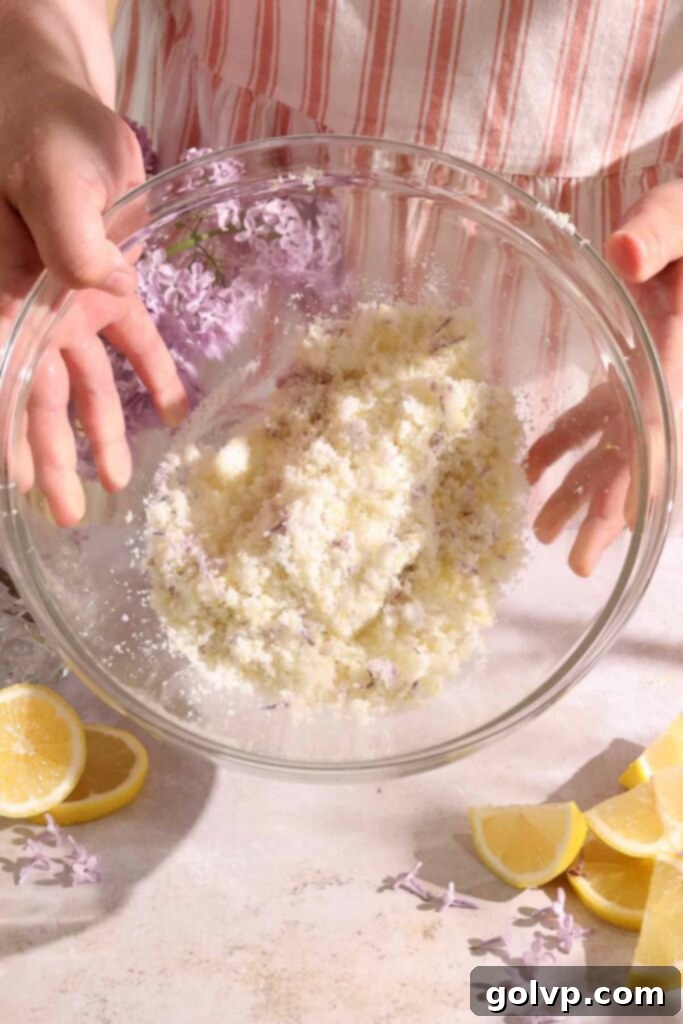 Close-up of sugar, lemon zest, and lilac flowers being rubbed together to release fragrance