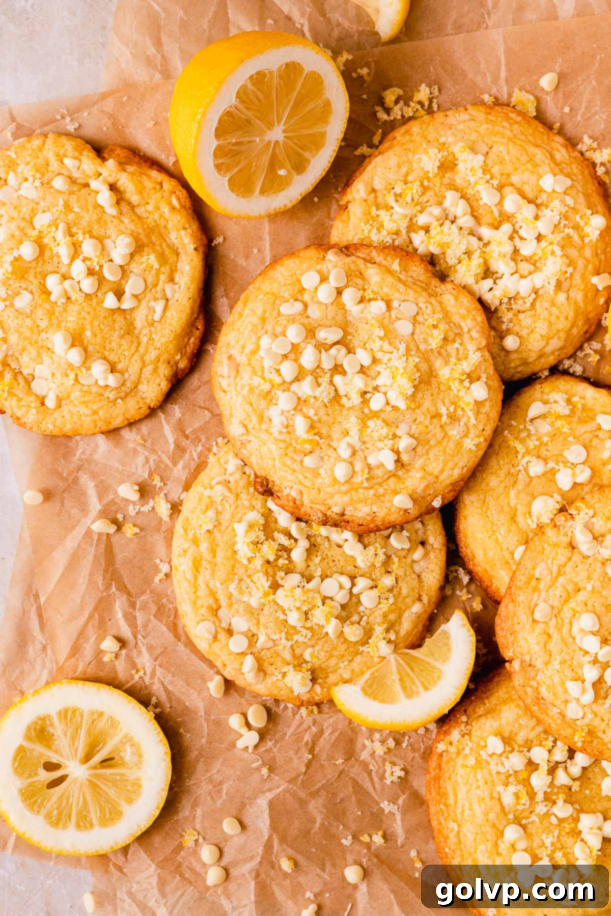 Freshly baked lemon white chocolate cookies topped with mini white chocolate chips and a sprinkle of lemon zest sugar, glistening invitingly.