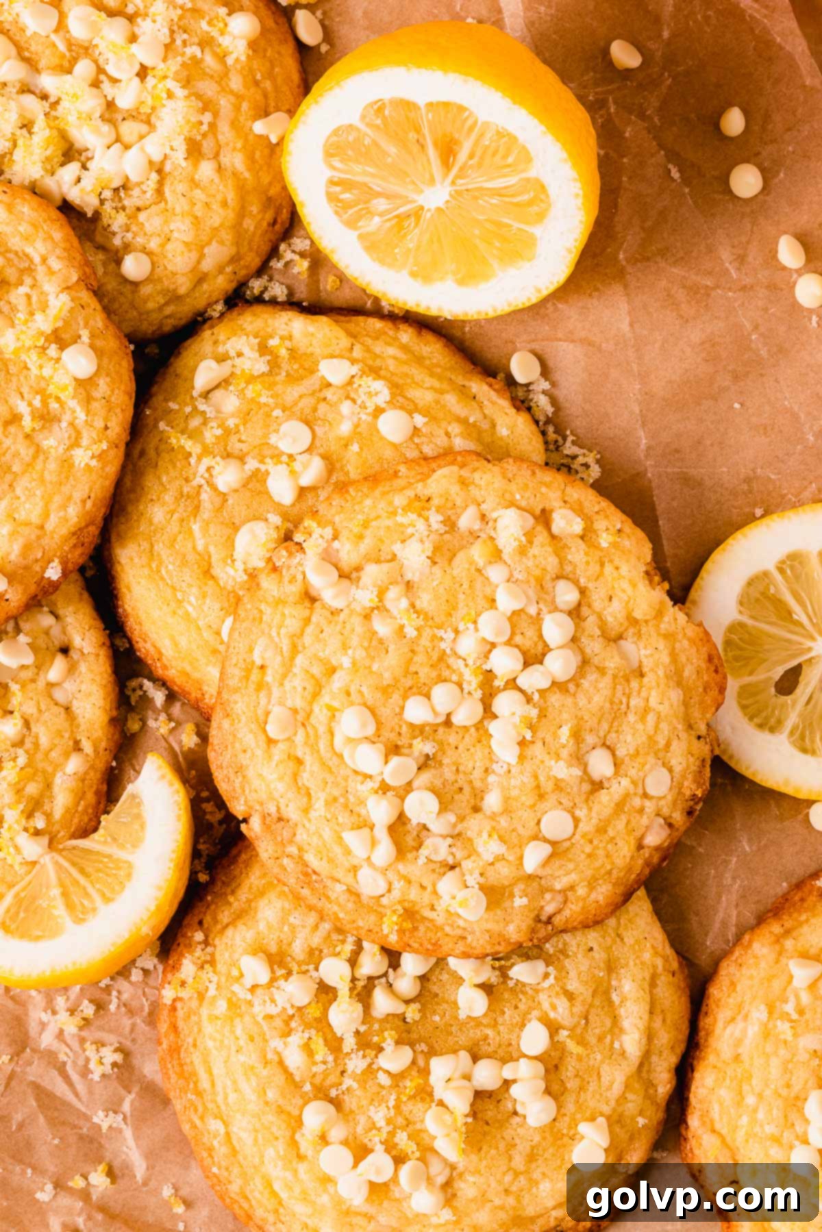 Warm lemon white chocolate cookies on parchment paper, freshly topped with mini white chocolate chips and lemon zest sugar.