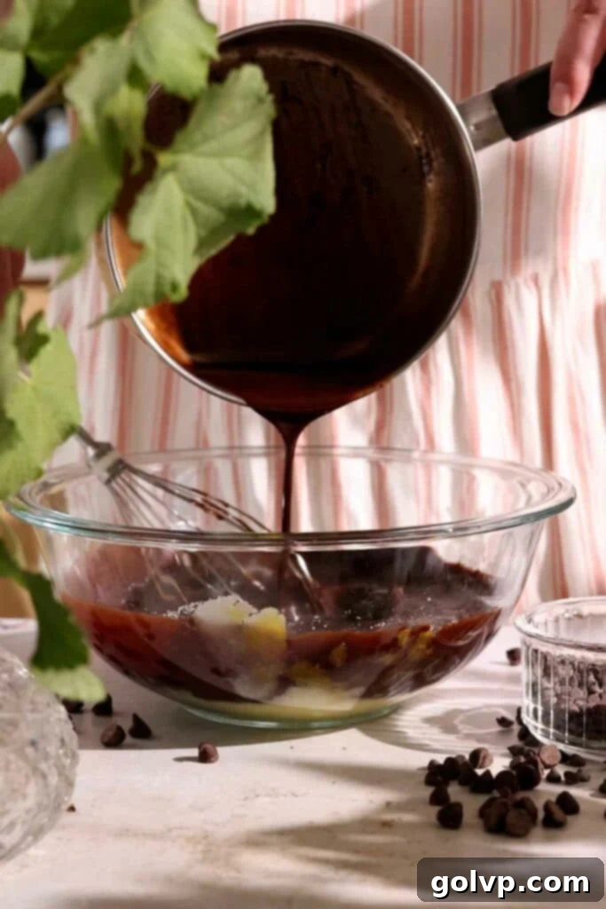 Pouring the melted butter and chocolate mixture into the wet ingredients for the cake batter.