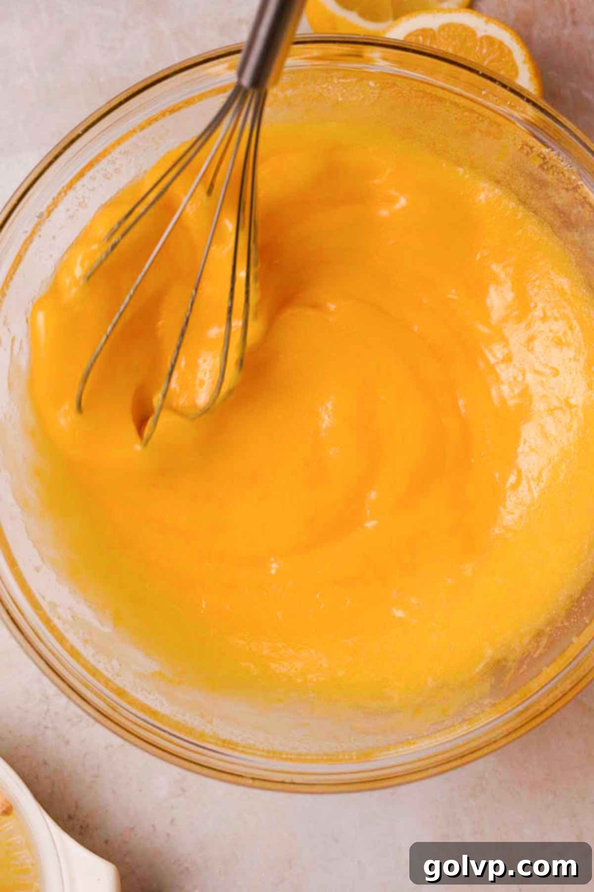 whisking lemon sugar, eggs, melted butter, and lemon juice with a wire whisk in glass bowl