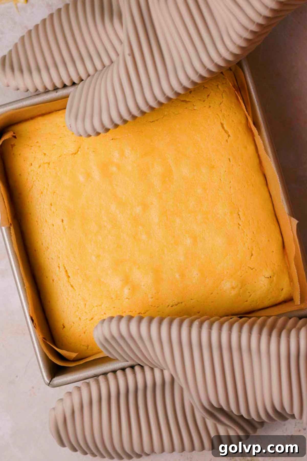 holding baked lemon brownies in baking pan with silicone oven mitts