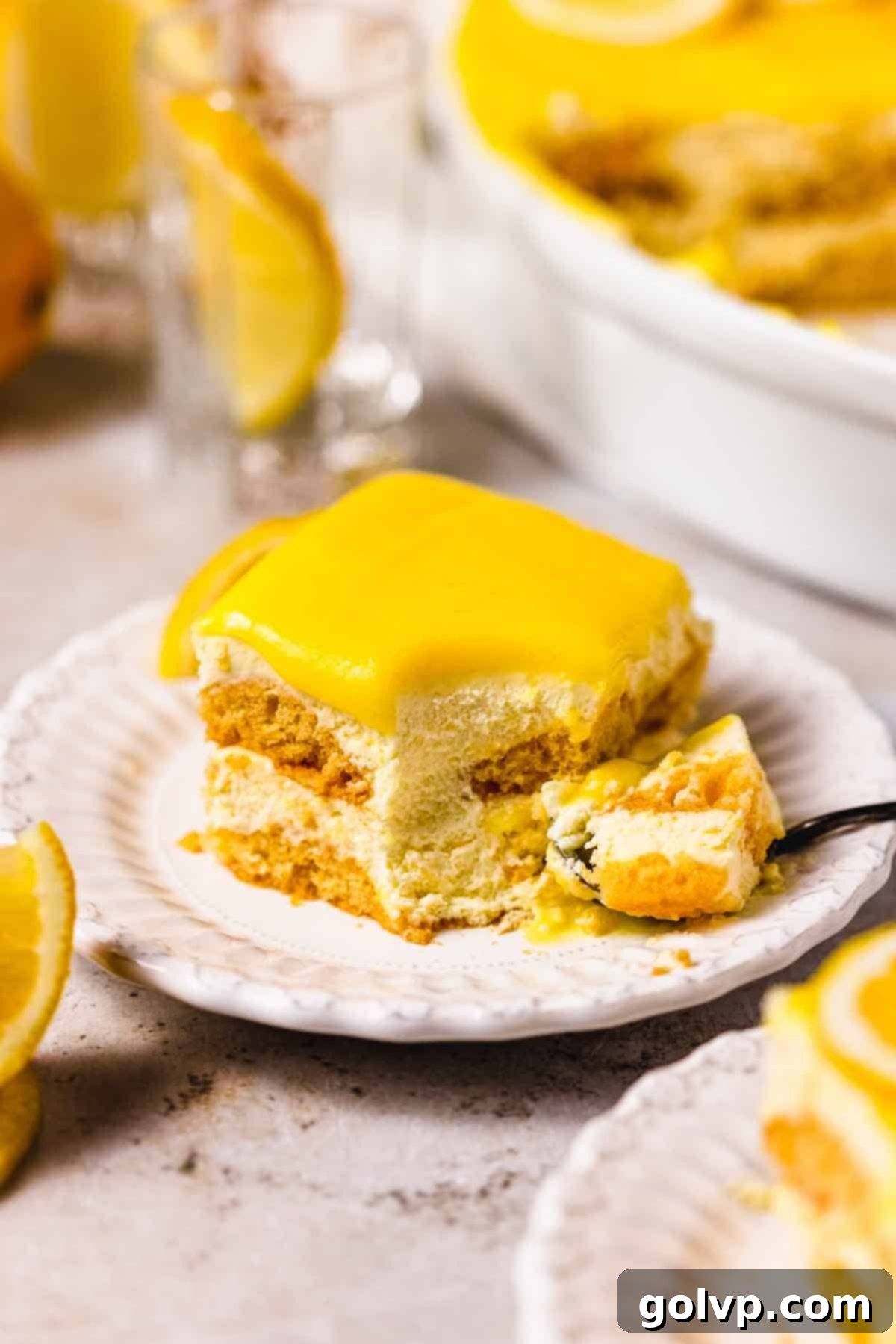 slice of creamy lemon tiramisu on white plate topped with lemon curd
