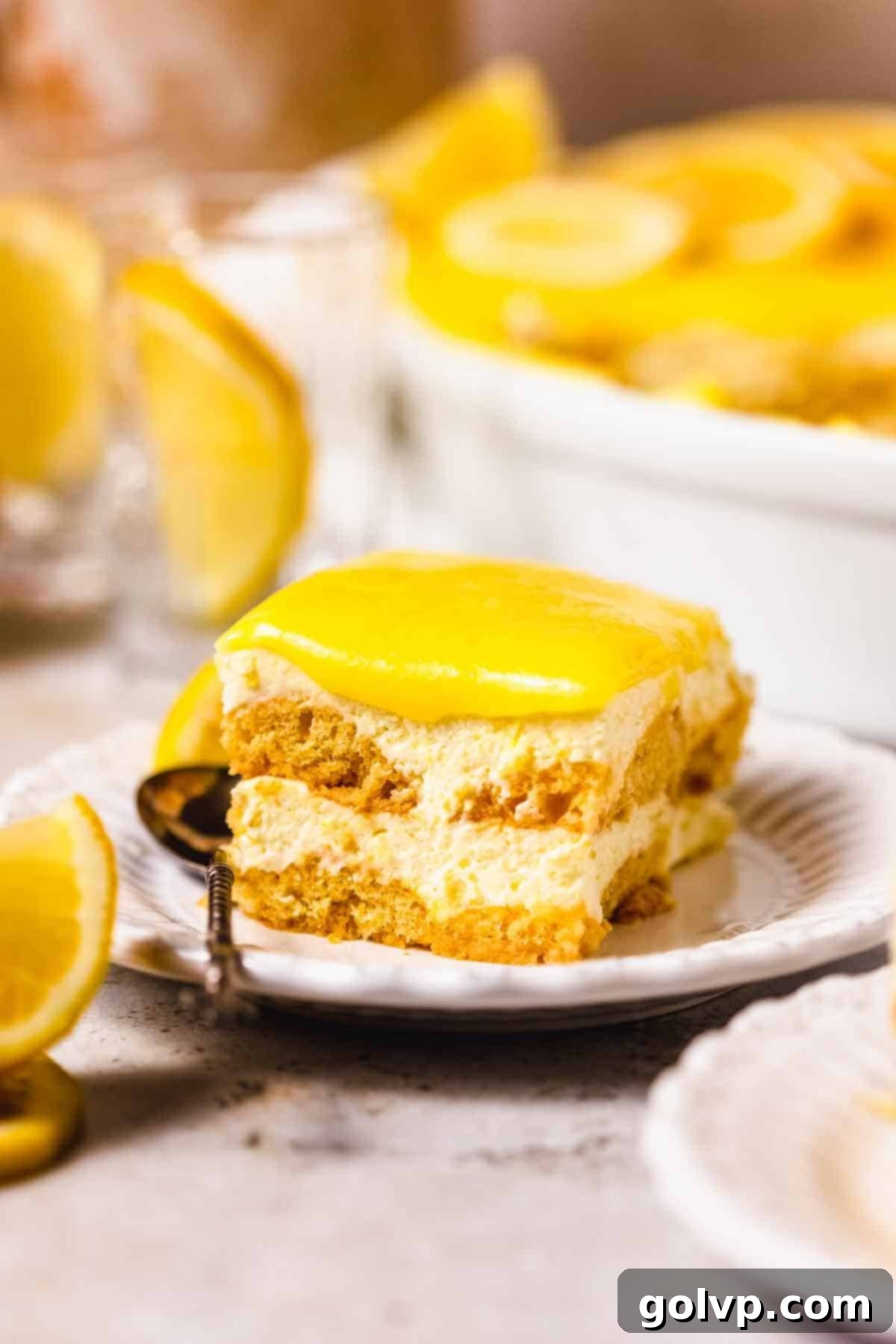 slice of lemon tiramisu on a plate with ladyfinger layers and topped with lemon curd