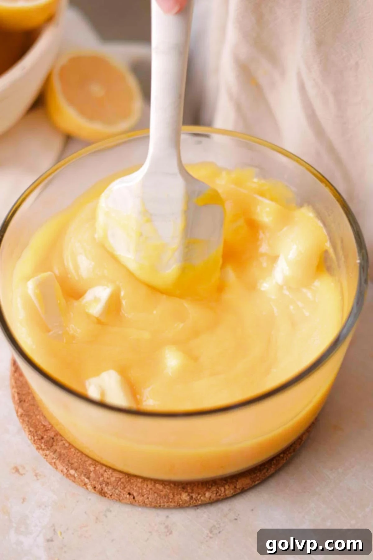stirring butter into lemon curd in glass bowl