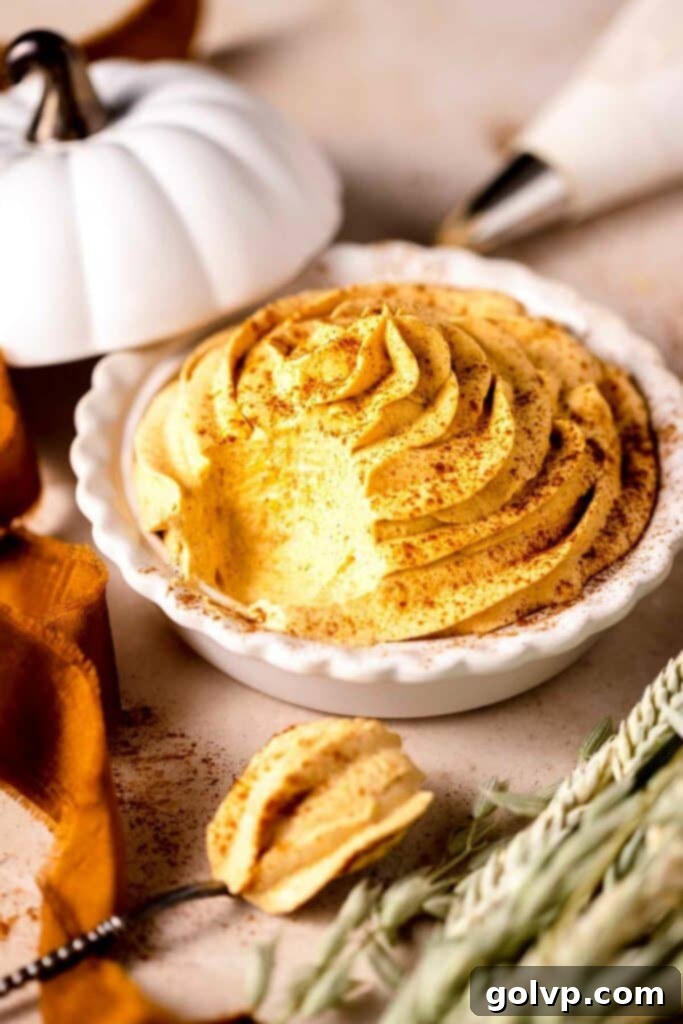 piped pumpkin whipped cream in a mini pie plate with pumpkin spice sprinkled on top