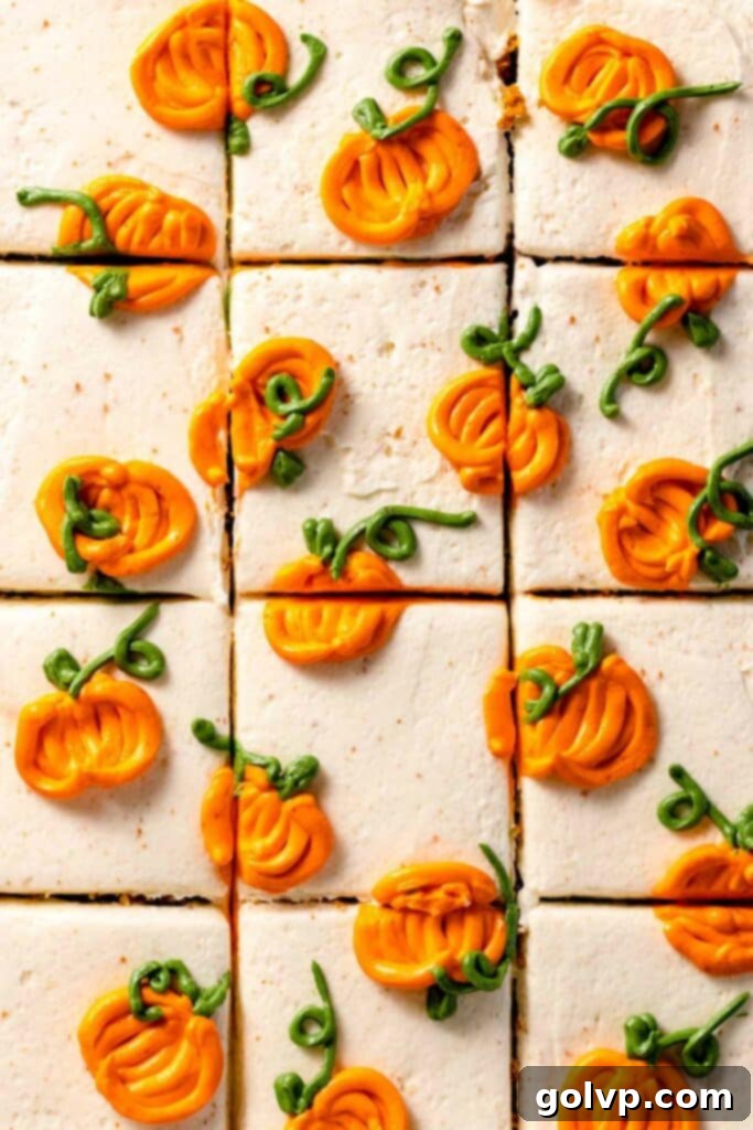 Sliced pumpkin cake frosted with creamy white frosting and decorative piped mini pumpkins, ready for serving.