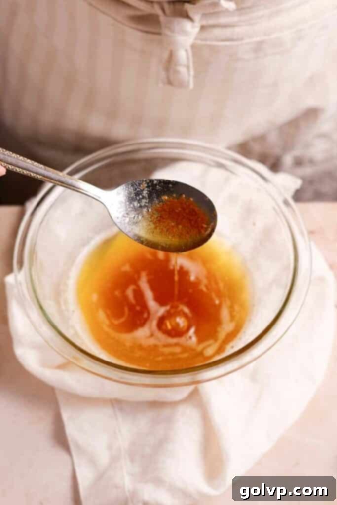 A close-up shot of melted brown butter in a spoon, showcasing its rich amber color and the tiny caramelized specks that give it its distinctive nutty flavor.