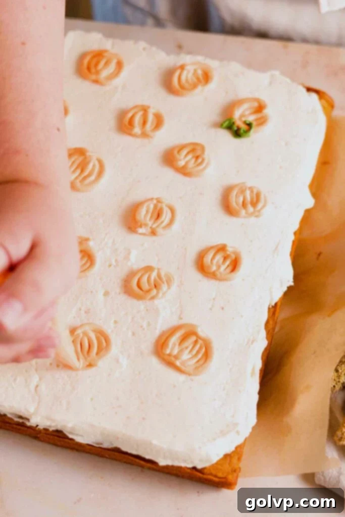Orange frosting is piped onto a white-frosted cake to create mini pumpkin shapes, with segment lines being added for detail.