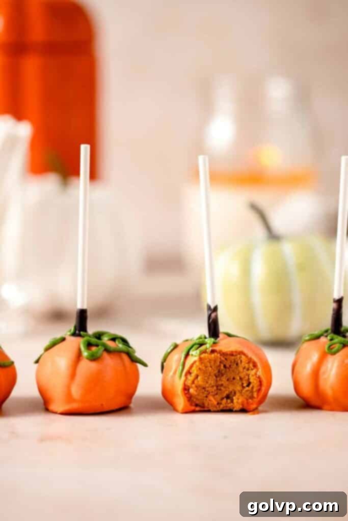 Pumpkin cake pops in a row with a candle in the back