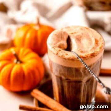 Iced coffee topped with pumpkin cold foam and spoon with mini pumpkins surrounding