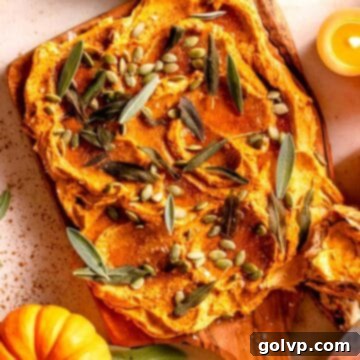 Pumpkin infused butter spread on a board with sage leaves and mini pumpkins