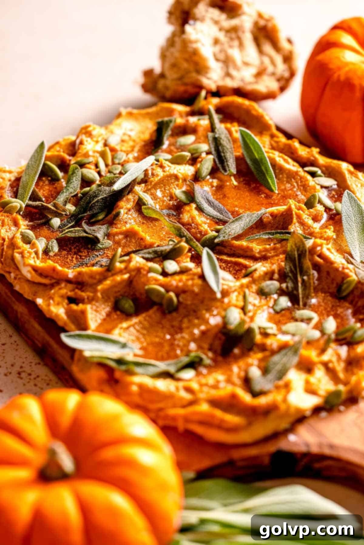 wooden board topped with pumpkin infused butter, sage leaves, seeds, and mini pumpkins on the side