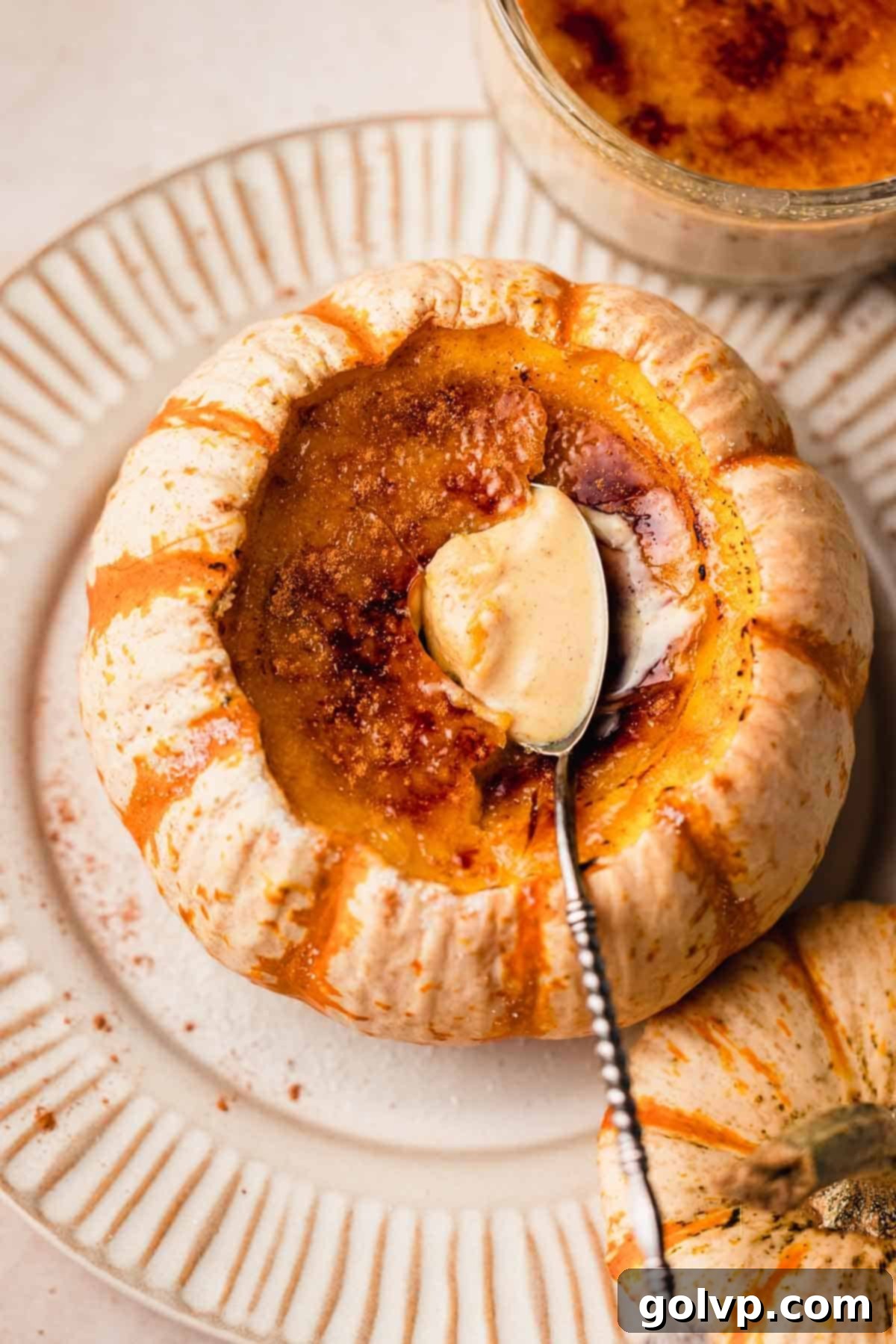 creme brulee with spoon inside of a mini orange and white pumpkin